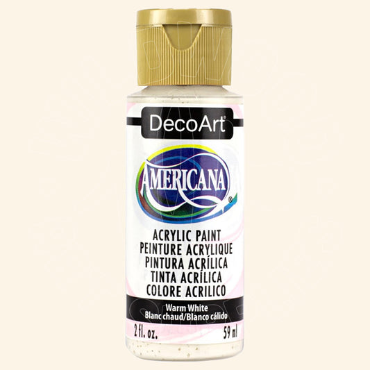 A bottle of DecoArt Americana acrylic paint in the color Warm White, featuring a gold cap and a white label with black and colorful branding.