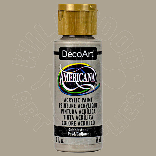 A bottle of DecoArt Americana acrylic paint in the 'Cobblestone' color, featuring a metallic silver-gray paint container and a gold cap, set against a solid taupe background.