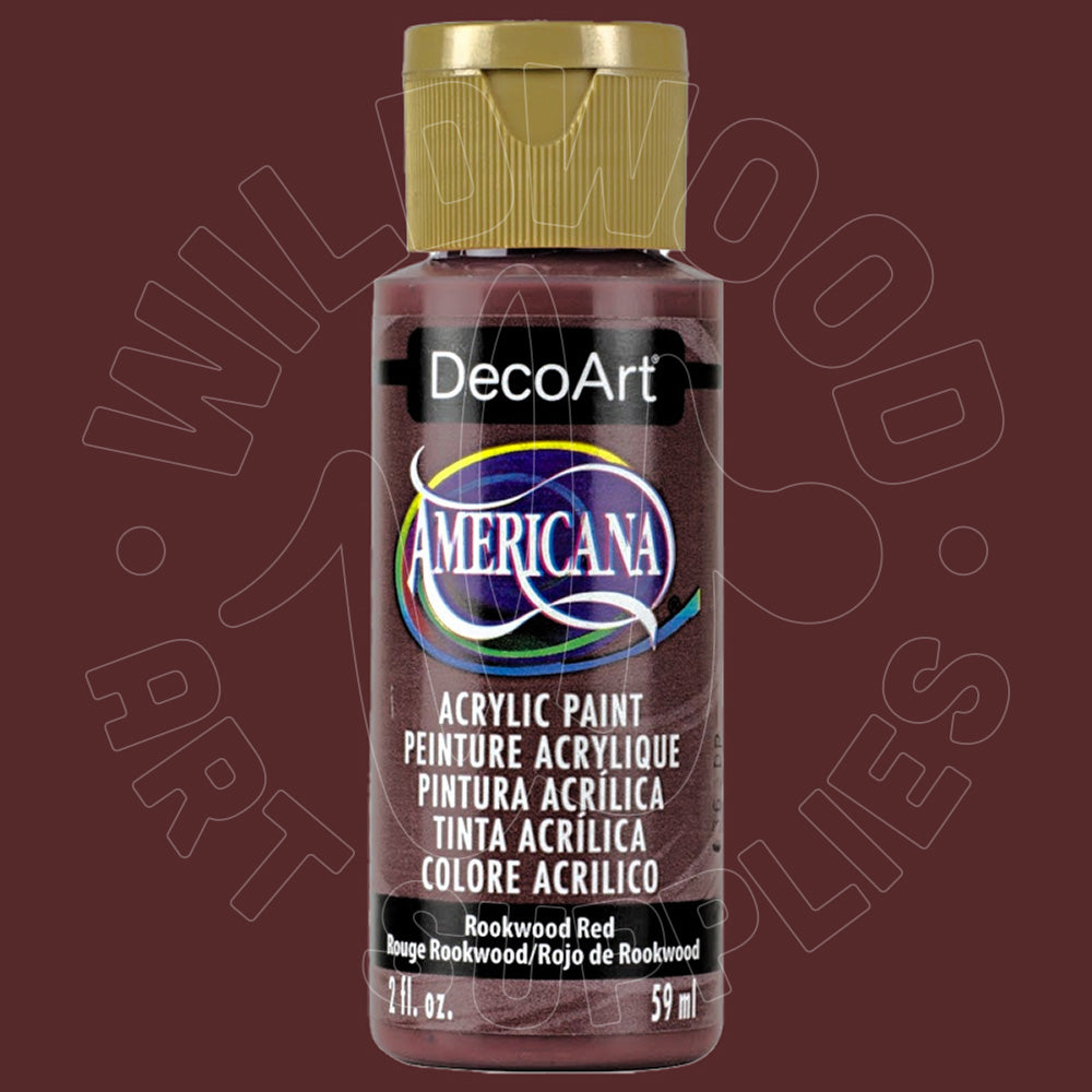 A bottle of DecoArt Americana acrylic paint in the color 'Rockwood Red', featuring a gold cap and a black label with multicolor accents, set against a solid dark reddish-brown background.