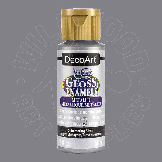 A bottle of DecoArt Metallic Enamel Acrylic Paint in Shimmering Silver, featuring a gold cap and a silver label with purple and gold accents, set against a solid gray background.