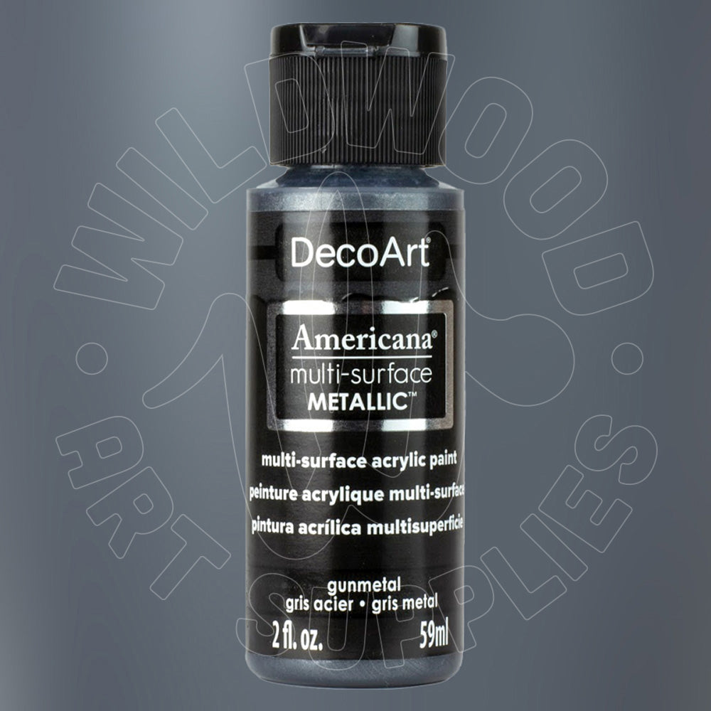 A bottle of DecoArt Americana Multi-Surface Metallic acrylic paint in gunmetal gray, featuring a black cap and a black label with white text, set against a dark gray gradient background with a faint watermark.