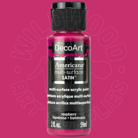 A bottle of DecoArt Americana multi-surface satin acrylic paint in raspberry, featuring a black cap and black label with white text, set against a solid magenta-pink background.