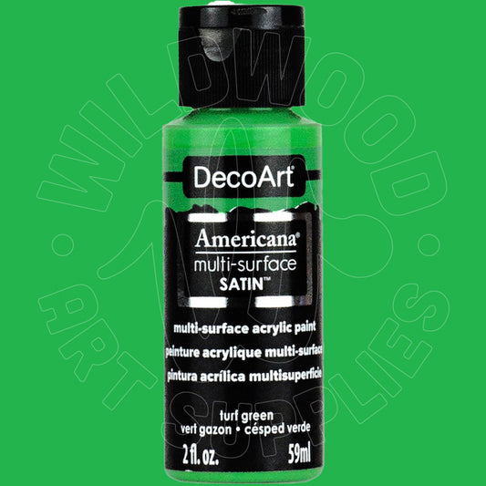 A bottle of DecoArt Americana multi-surface satin acrylic paint in turf green, shown against a solid green background with a faint watermark.