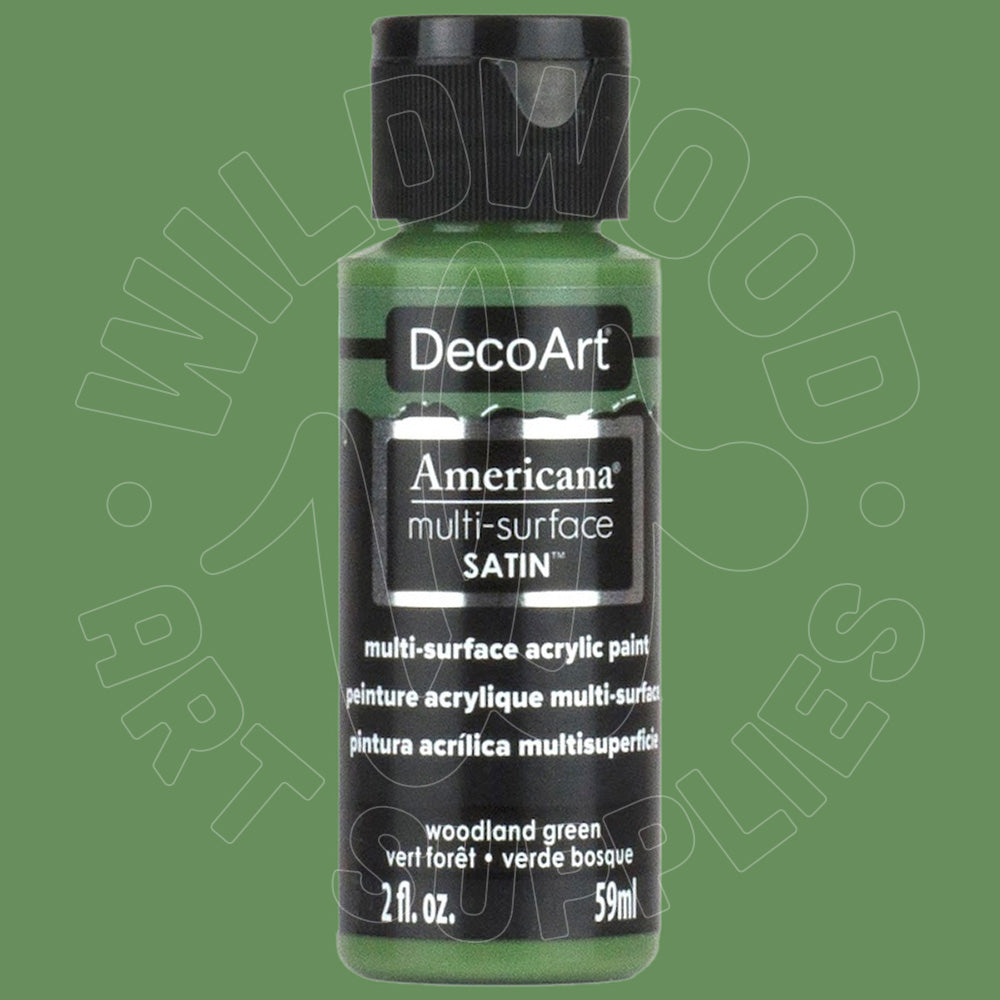 A bottle of DecoArt Americana multi-surface SATIN acrylic paint in the color 'woodland green', featuring a black cap and black label on a solid green background.